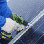 A technician drilling a solar panel into place.