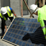 A solar panel held by two workers.
